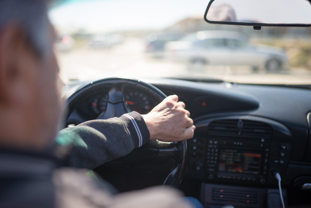 Mains d'un conducteur senior sur le volant, illustration du débat sur la fin du permis de conduire à vie en Europe.