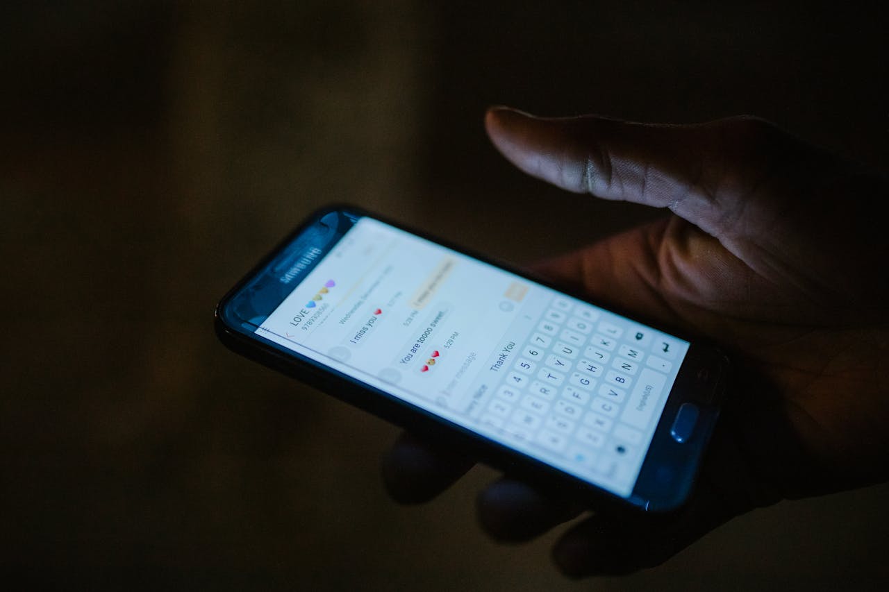 Main tenant un smartphone affichant une notification illustrant les arnaques par SMS et phishing